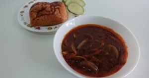 A top-view picture of a white bowl filled with the final sambal ikan bilis product, there's a bread off to the left of the picture.